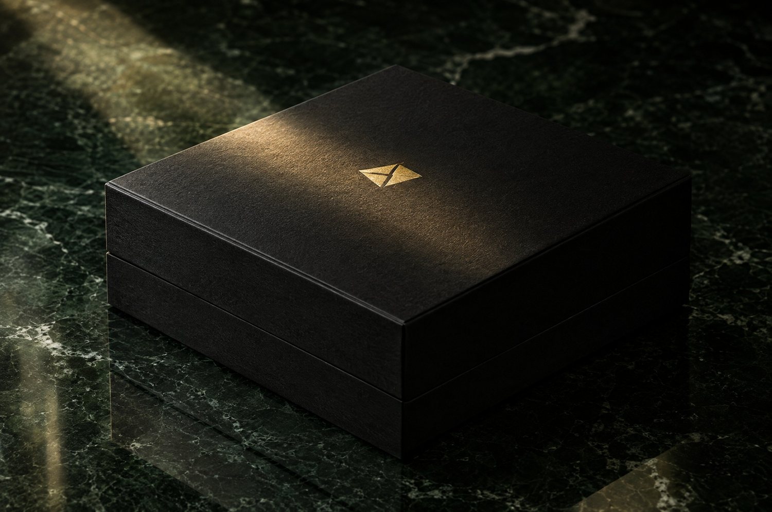 Matte black box with a gold foil emblem on dark green marble